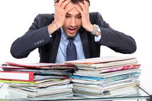 Photo of a panicked person surrounded by paperwork. MarkBook software could help out